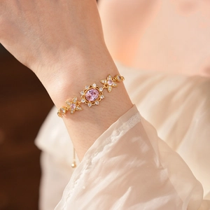 Detailed close-up of a vintage gold bracelet featuring pink oval gems and floral accents