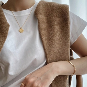 Detail of layered gold coin necklace and link bracelet with star charm on model