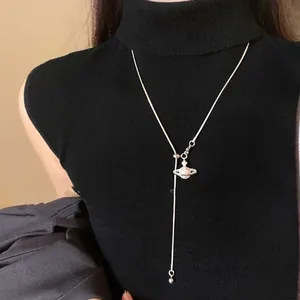 Collier Saturne argenté sur mannequin en pull noir montrant le bijou en forme de Y