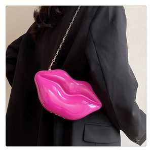 Detailed view of glossy hot pink lip-shaped crossbody bag with gold chain on model