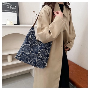 Close-up of vintage denim tote bag with floral patterns and brown leather shoulder strap