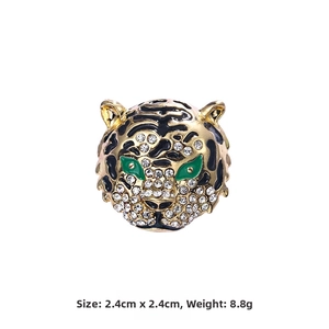 Detail of tiger head brooch in gold alloy with green crystal eyes and black enamel stripes