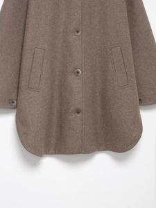 Dettaglio del cappotto di lana da donna con bottoni monopetto e orlo arrotondato