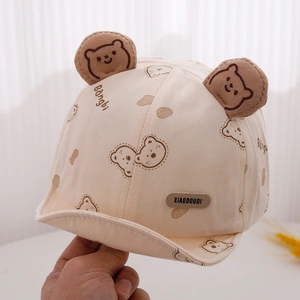 Detail of baby sun hat with cute 3D bear ears and cartoon print on beige fabric