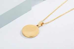 Close-up of golden stainless steel necklace with a circular tree of life pendant detail