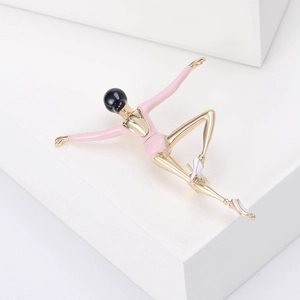 Detail of a gold ballerina brooch featuring a pink enamel tutu on a minimalist background