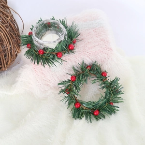 Close-up of artificial Christmas holly berry candle ring with green pine needles on white rug