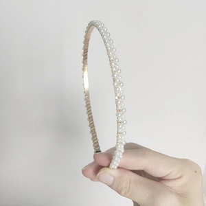 Close-up of golden metal headband with white pearls in a double-row elegant design