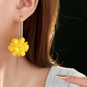 Dettaglio della modella che indossa orecchini a fiore in acrilico giallo e diamanti
