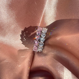 Close-up of S925 sterling silver rings with pink and clear heart-shaped zircons on silk