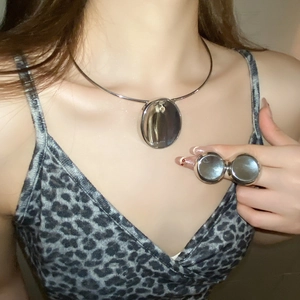 Detail of silver oval mirror necklace and double ring set worn by fashion model