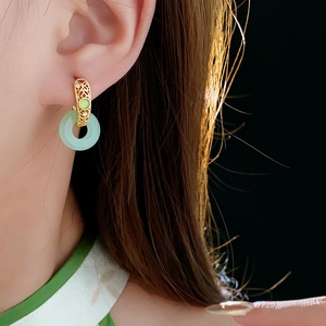 Détail de boucles d'oreilles plaquées or 18 carats avec jade vert sur un mannequin