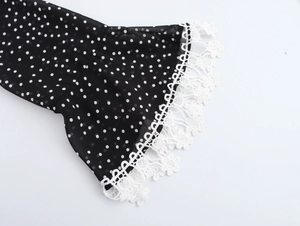 Close-up of black polka dot dress flare sleeves with delicate white lace trim details