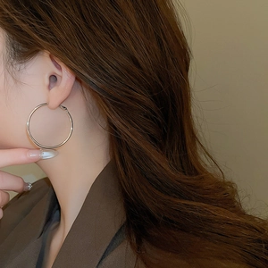 Close-up of minimalist silver hoop earrings with a polished metallic finish on model