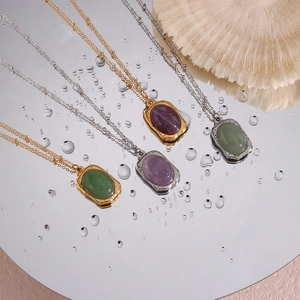 Detailed view of vintage oval gemstone necklaces on a reflective mirror with water drops