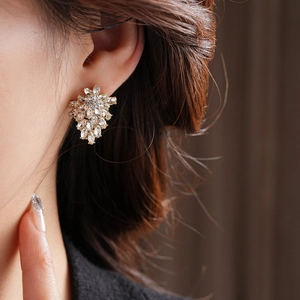 Close-up of model wearing flower leaf earrings with marquise crystals and gold finish