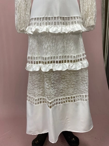 Dettaglio del pizzo floreale, della gonna a balze e dell'uncinetto sul vestito bianco