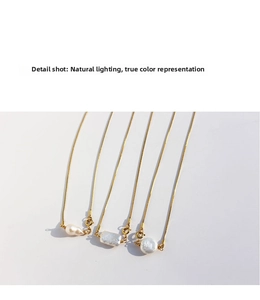 Detail shot of golden snake chains with various Baroque pearl pendants in natural light