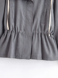 Detail of dark grey windbreaker featuring adjustable drawstring waist and utility cargo pockets