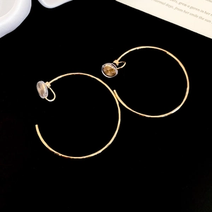 Vue détaillée de boucles d'oreilles clips dorées avec coussinets en silicone sur fond noir