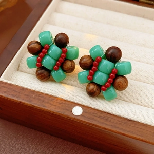 Detail of ethnic earrings with green resin cubes and brown wood beads in a wooden box