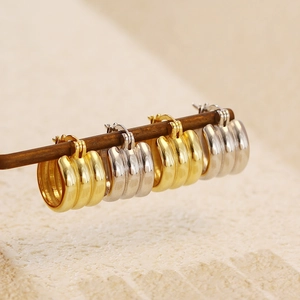 Close-up of multilayered gold and silver s925 sterling silver hoop earrings on a wood rod