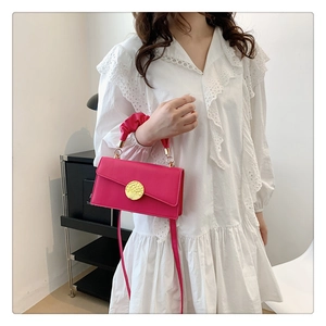 Détail du sac bandoulière rose fuchsia avec boucle dorée et poignée ornée de fronces
