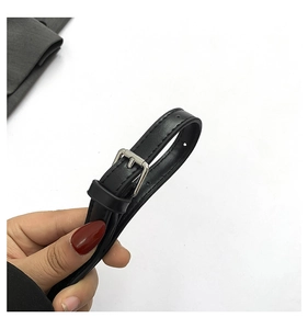 Detail of black leather shoulder strap with silver metal buckle and adjustable holes