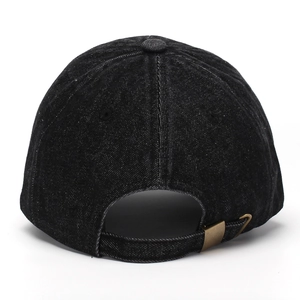 Detail view of adjustable bronze metal buckle and stitching on black denim baseball cap