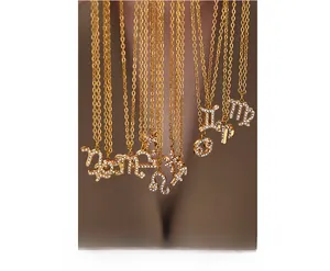 Detail of layered gold zodiac necklaces with sparkling crystal pavé on a female model