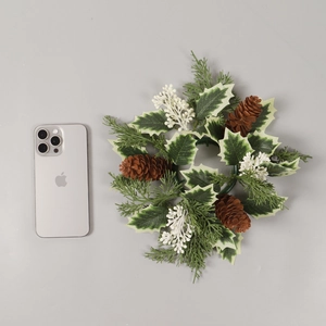 Christmas candle ring with frosted leaves and pine cones on a grey background