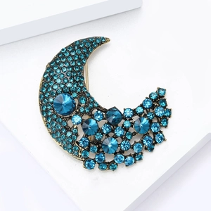 Detailed close-up of crescent moon brooch with blue rhinestones and bronze metal finish