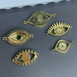 Golden evil eye pendants with zircon inlays on grey textured surface for jewelry making