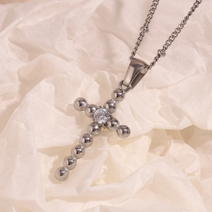 Macro shot of silver stainless steel cross pendant featuring central cubic zirconia bead