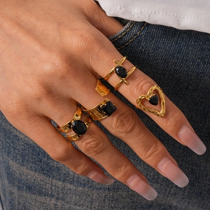 Vue détaillée de quatre bagues dorées de style vintage avec pierres noires sur modèle