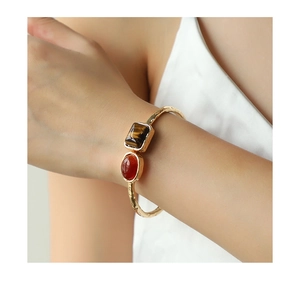 Goldenes Vintage-Armreif mit Tigerauge und rotem Achat am Handgelenk des Models