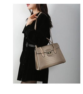 Detail showing high-capacity camel tote bag with crocodile pattern and metallic lock closure