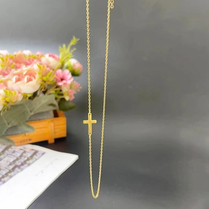 Dettaglio della collana a doppio strato con pendente a croce dorata e perle in acciaio