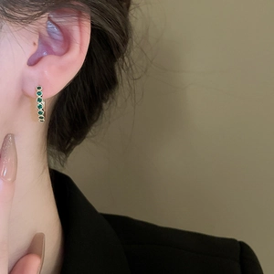 Créoles dorées élégantes avec pierres de zircon vert portées sur un mannequin