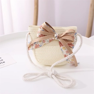 Detailed view of cream straw woven crossbody bag for kids with pink floral bow accent