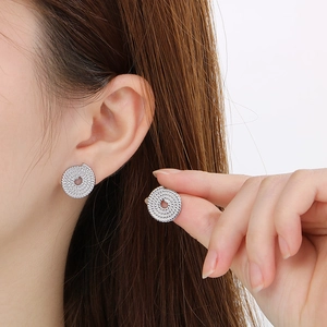 Minimalist spiral knot stud earrings in silver stainless steel on model ear
