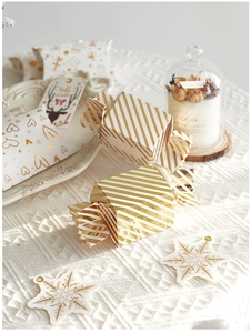 Exquisite gold-stamped Christmas candy box and reindeer gift tags on woven tablecloth