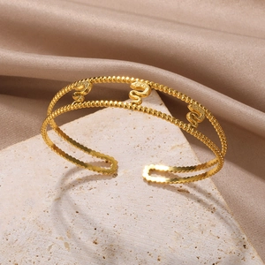 Detail of gold-plated stainless steel open cuff with snake motifs and beaded edges