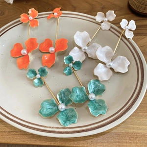 Detail of floral enamel earrings with pearls in orange, white, and green styles