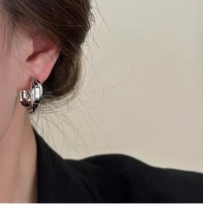 Vue détaillée d'un clip d'oreille géométrique torsadé argenté porté par un mannequin