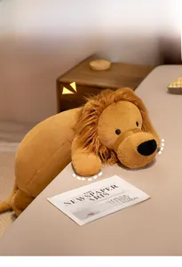 Close-up of a soft lion plush toy with brown mane lying on a cozy bed in home setting