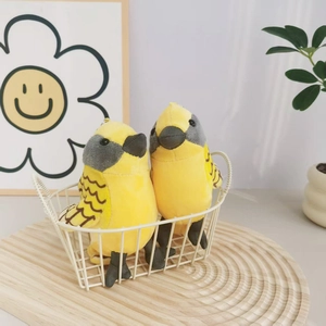 Cute yellow plush bird keychain charms in a white basket with cozy home background