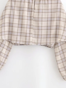 Close-up of plaid crop top featuring an elastic hem in beige, brown, and light purple tones