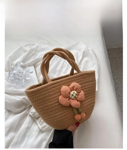 Detail of khaki woven cotton tote bag featuring a pink fabric flower and dual handles