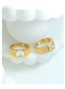 Macro view of 18K gold plated steel rings with rectangular zircon on white ceramic tray